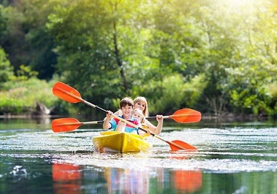 Child with paddle on kayak. Summer camp for kids. Kayaking and canoeing with family. Children on canoe. Family on kayak ride. Wild nature and water fun on summer vacation. Camping and fishing.